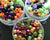 three clear containers filled with Halloween beads on a dark background